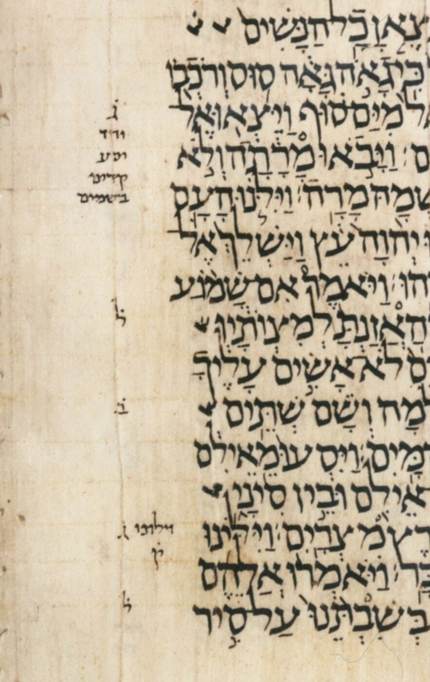 A column of medieval Hebrew manuscript writing, the consonants carrying small dots and strokes above, below and between them, with short notes in a smaller hand down the margin.