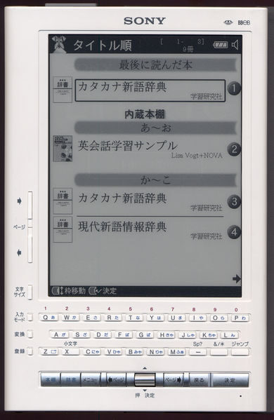 A white hand-held reading device marked Sony, its greyscale screen showing a list of Japanese book titles, with a full alphanumeric keyboard and a row of control keys along the lower half of the front.