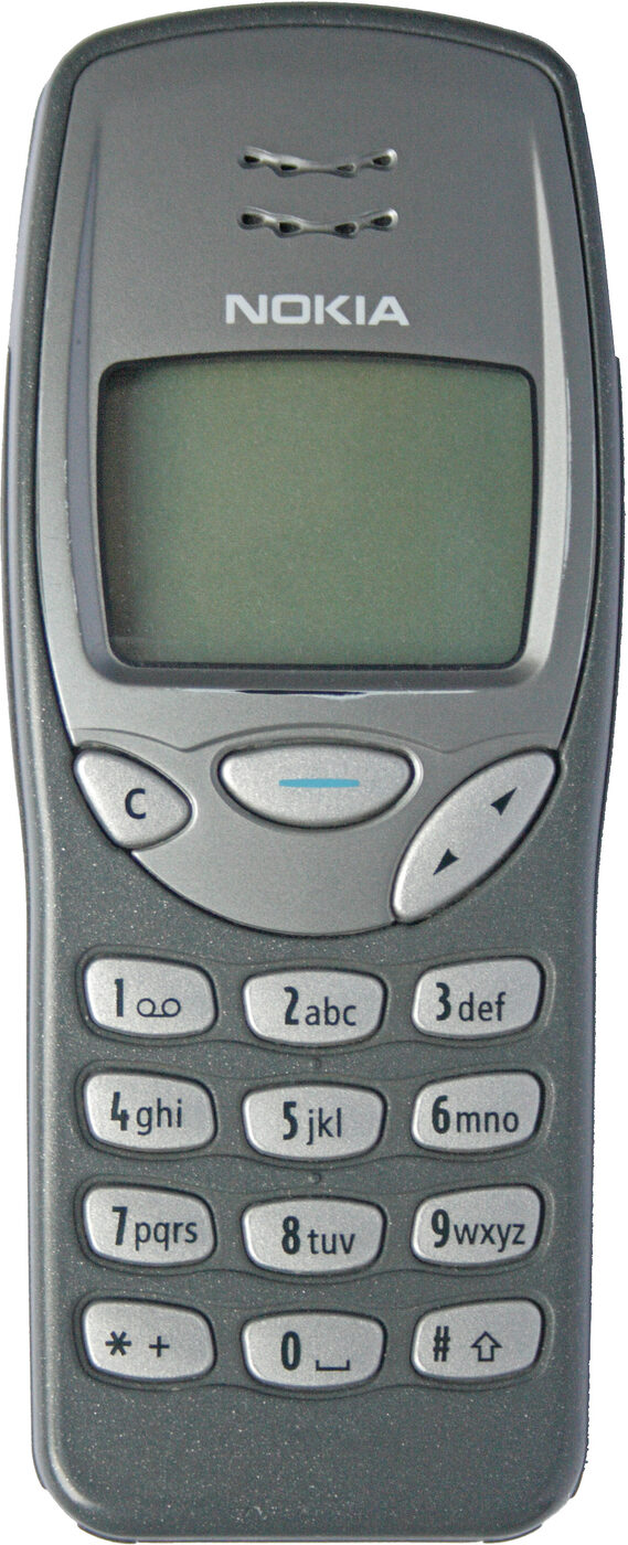 A small grey candybar mobile telephone with a monochrome screen above a numeric keypad and no external aerial, held against a plain background
