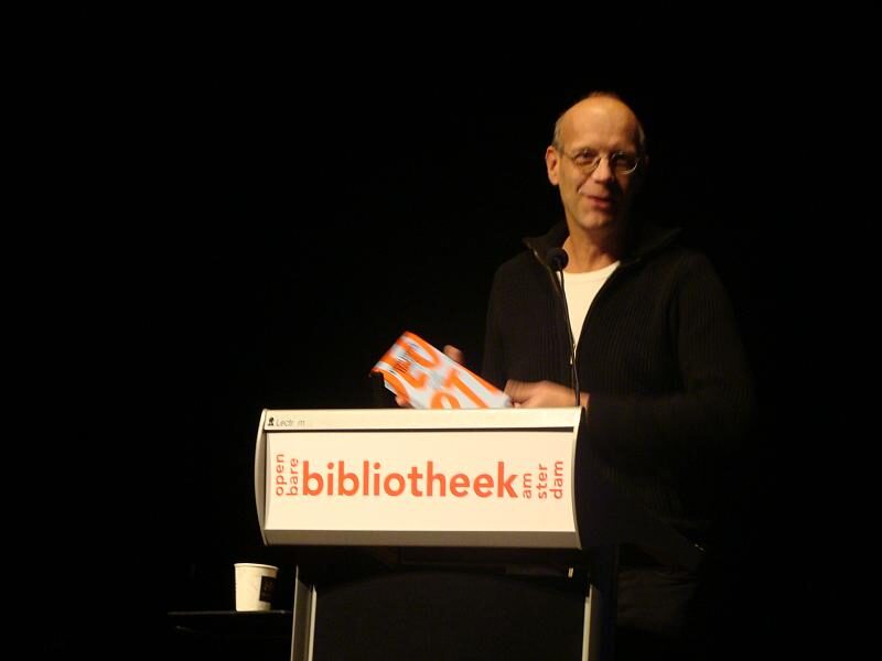 Geert Lovink, a man with glasses, photographed at a media event.