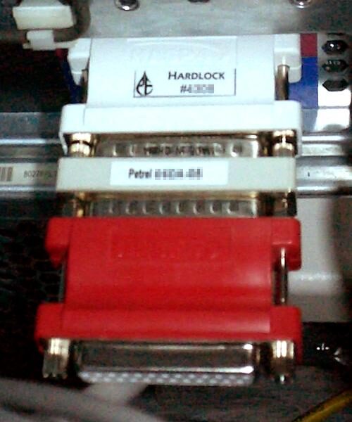 Several beige and grey plastic parallel-port dongles plugged into one another in a chain, their serial-number labels pixelated out.