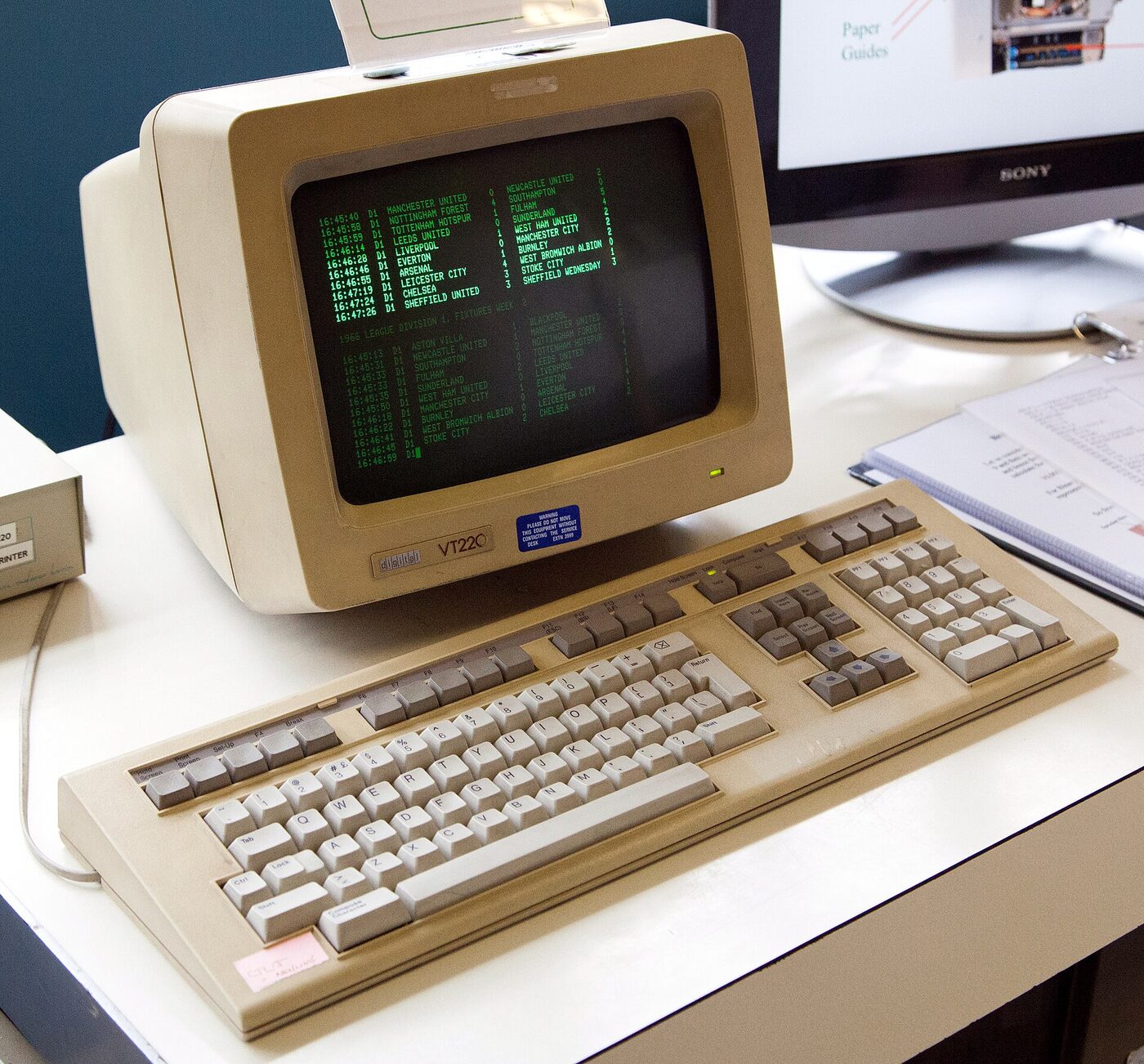 A beige DEC VT220 text terminal with a separate keyboard, its monochrome screen showing green columns of text.