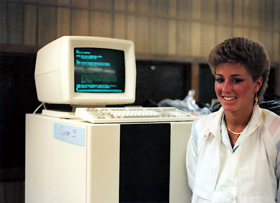 Several tall cabinet-style minicomputer units standing in a machine room, with a cathode-ray-tube console alongside.