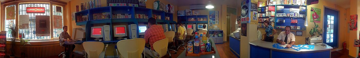Wide panoramic photograph of rows of desktop computers in use at an internet cafe in Istanbul in 2000.