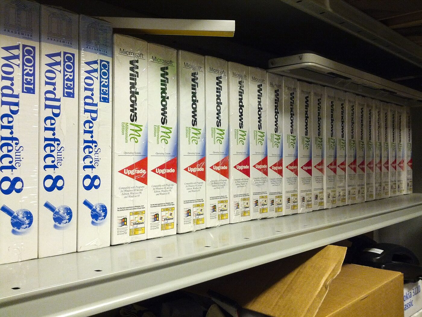 A stack of shrink-wrapped software boxes, most of them copies of Microsoft Windows Me, with several Corel WordPerfect Suite 8 boxes among them.