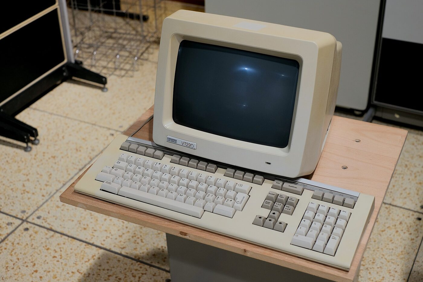 A beige Digital Equipment Corporation VT220 terminal with a dark, powered-off monochrome screen, standing on a wooden board beside its separate LK201 keyboard.