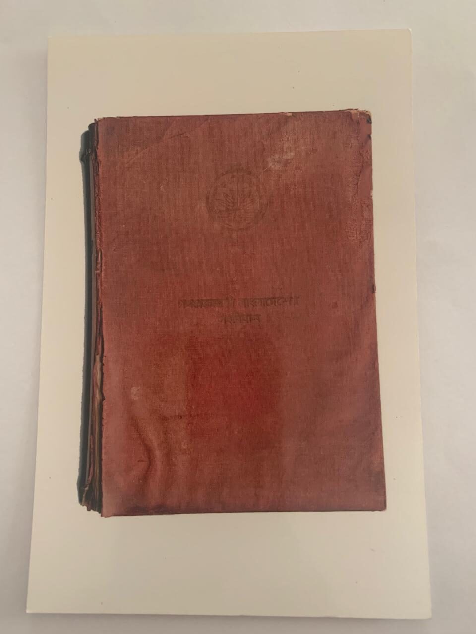 A dark leather book cover with an embossed decorative border and lettering in Bengali script, photographed straight on.