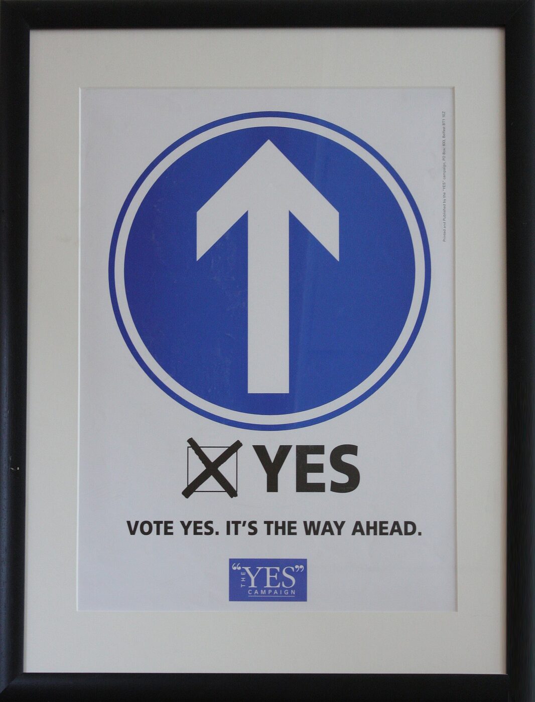 A framed 1998 campaign poster: a blue circular road sign with a white upward arrow, above a ticked box and the words “YES — Vote yes. It's the way ahead.”