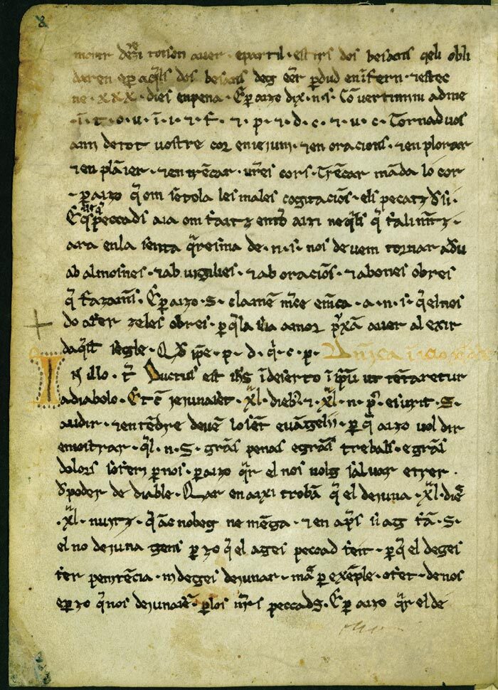 A vellum manuscript page carrying about thirty close-set lines of small brown medieval script, with a decorated initial and a cross drawn in the left margin.
