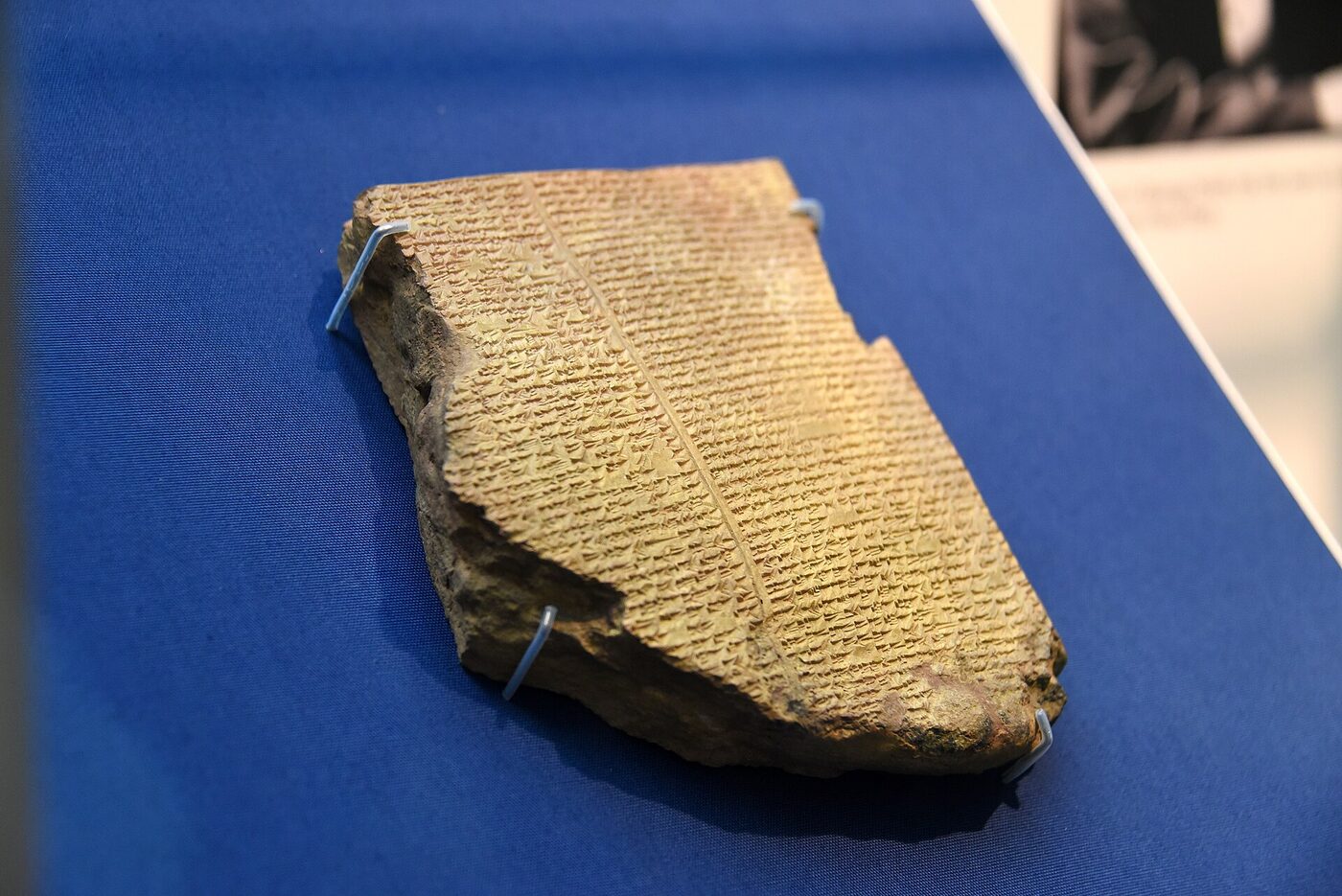 A broken rectangular clay tablet densely covered with rows of small wedge-shaped cuneiform signs.