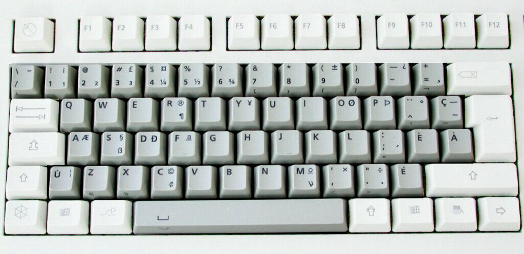 A photograph of a pale computer keyboard in the Canadian French layout, with E-acute, E-grave, A-grave and C-cedilla keys on the main block and dead keys for accents at its right-hand edge.