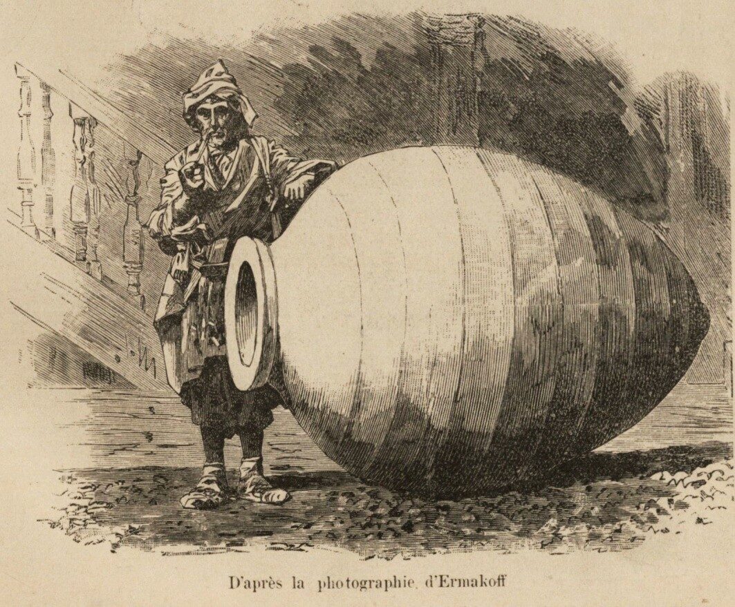Nineteenth-century engraving of a man in Caucasian dress standing beside a huge egg-shaped clay vessel without handles, lying on its side and taller than his waist, its round mouth facing the viewer.