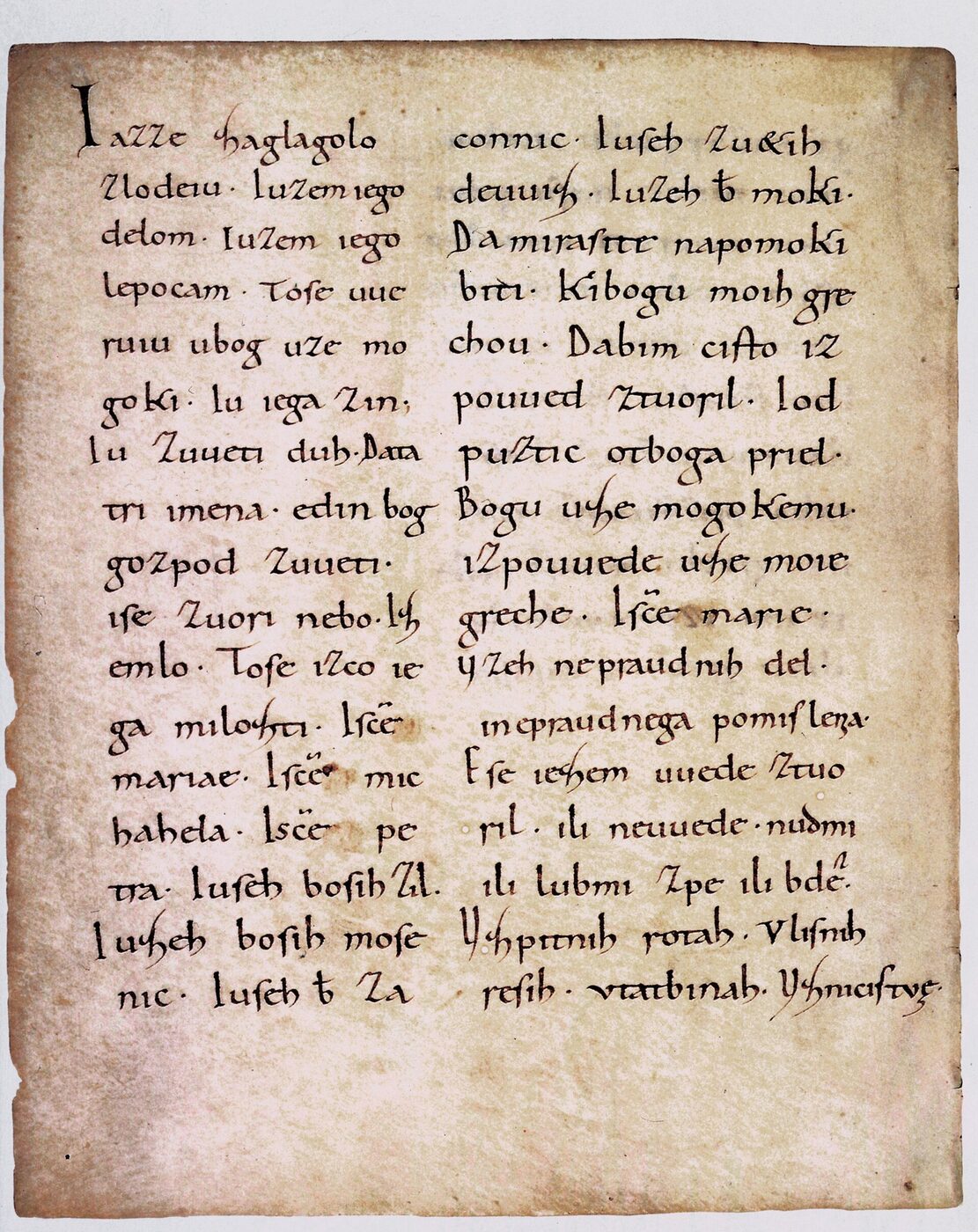 A parchment leaf written in two columns of dark Carolingian minuscule, the text in Latin letters but in an early Slavic language, with faint staining across the page.